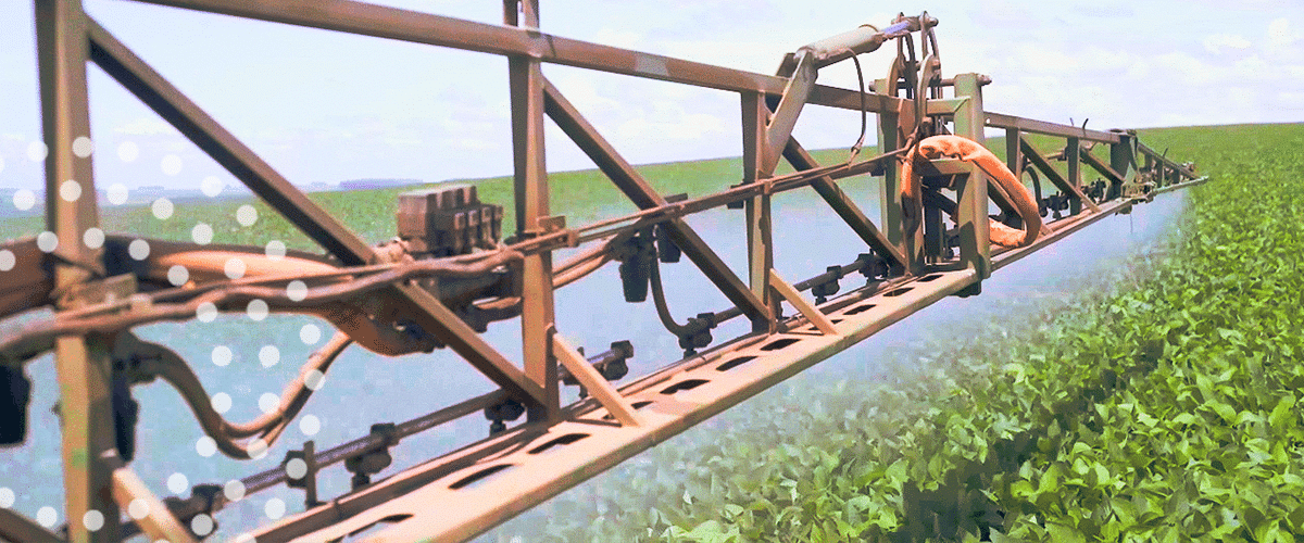 Farm machinery spraying fertilizer on a soybean field.